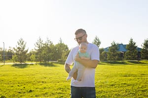 Happy father holding baby son outdoors in the park