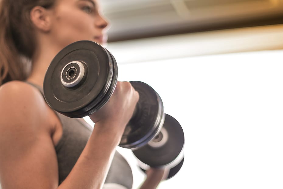 Fit woman with muscles in her 20s or 30s bicep curling dumbbells